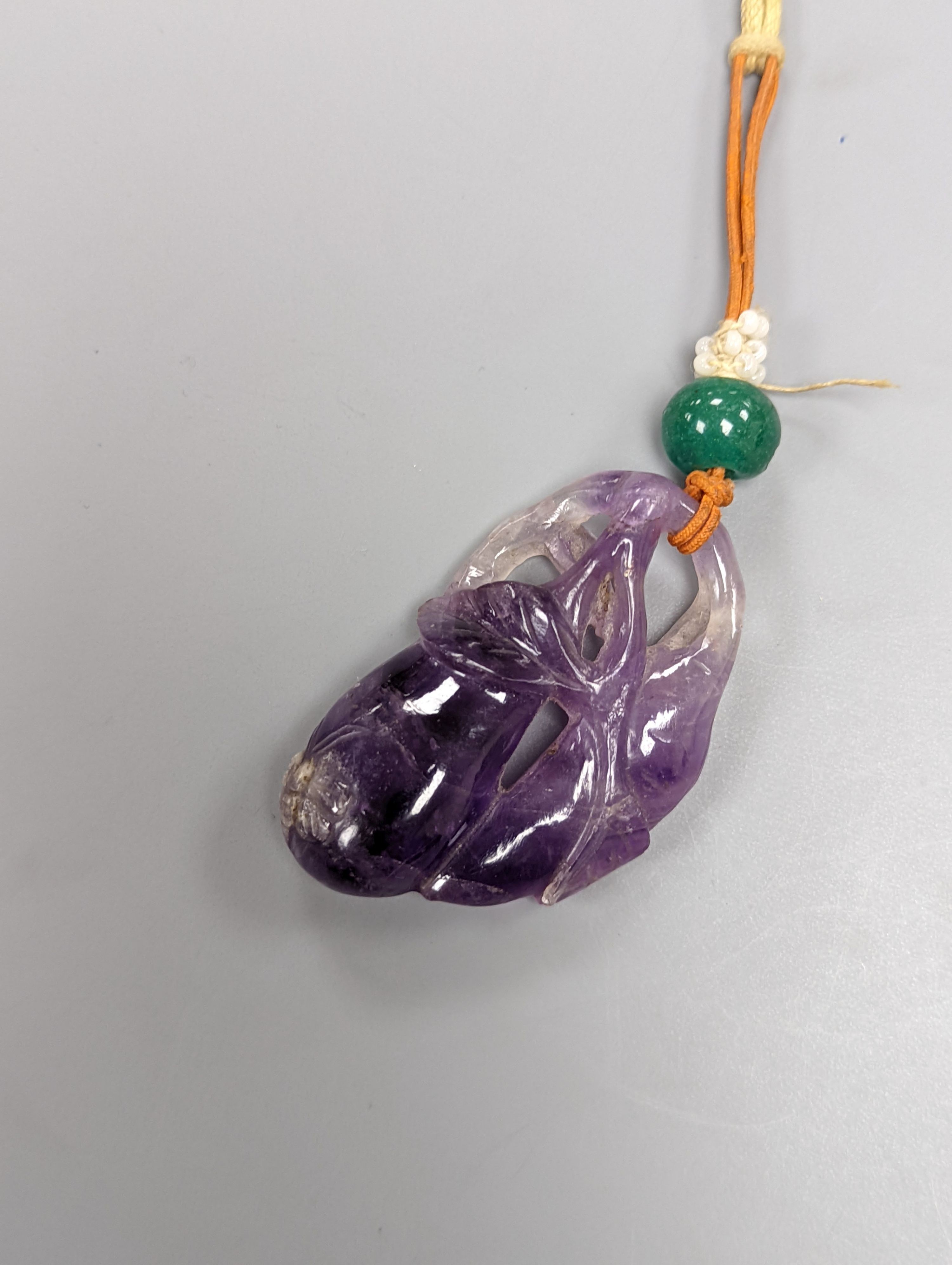 A 19th century Chinese carved amethyst pendant, 5cm on an ornate cord